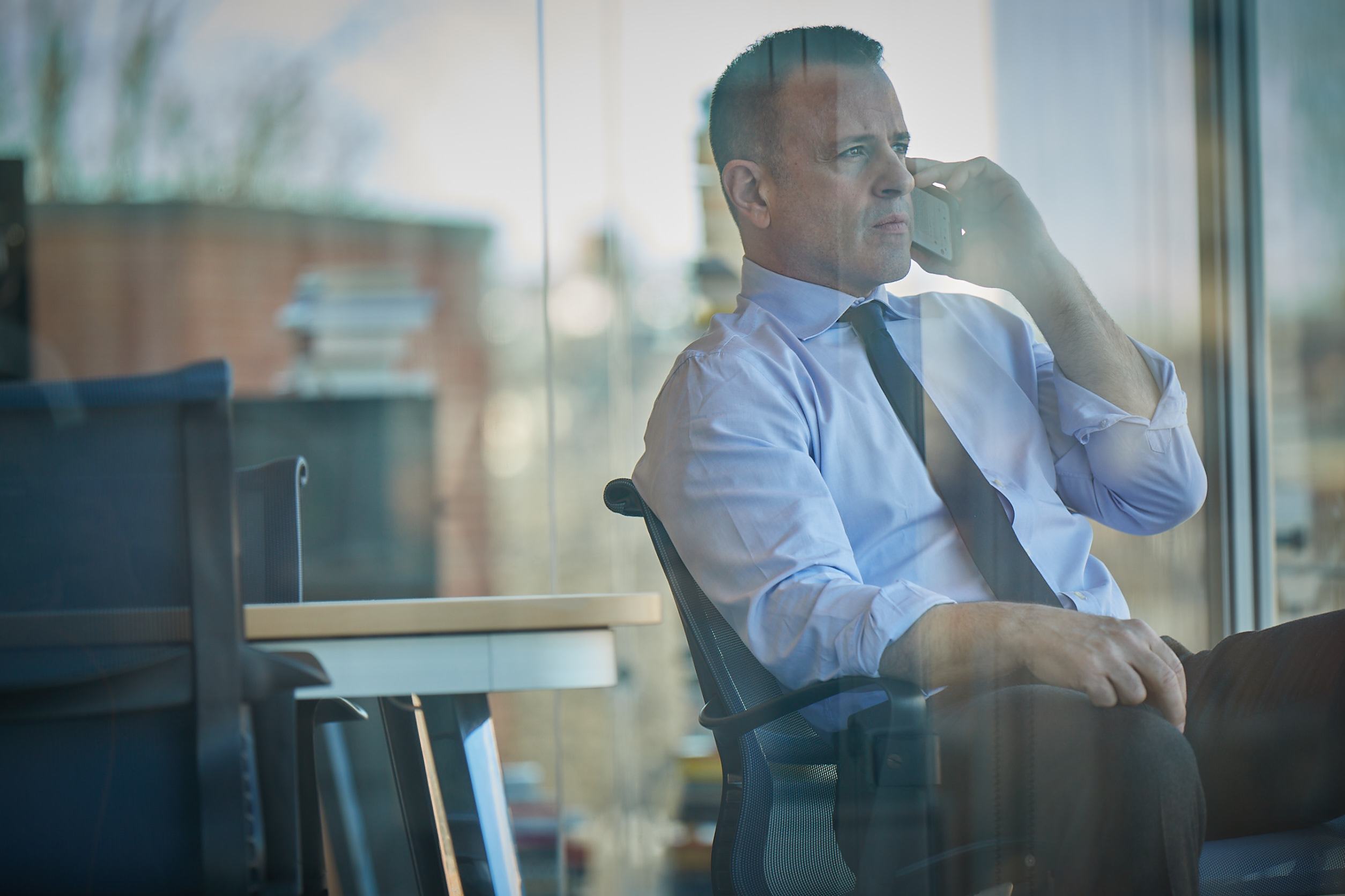Founder on phone at glass-walled office, contemplating next move